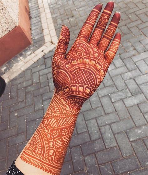 A Persons Hand With Henna On It And Brick Walkway In The Background