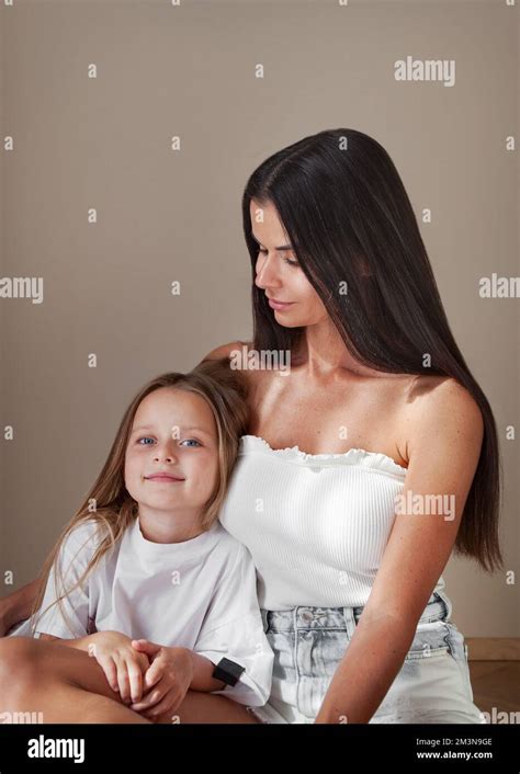 Mother And Daughter Portrait Beautiful Mom Embrace Girl In White Casual Clothes While She Look