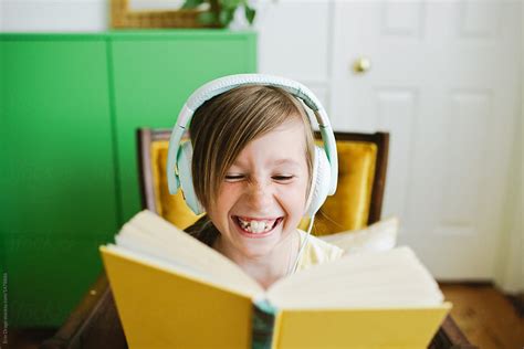View Young Girl Reading Along While Listening To A Book By Stocksy
