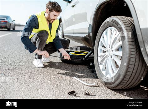 Man Lifting Car With The Jack Changing The Wheel On The Roadside Stock Photo Alamy