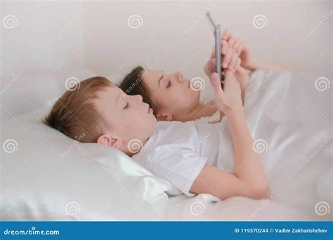 Mom And Son Wake Up And Browsing Internet In Their Mobile Phones Side View Stock Photo Image