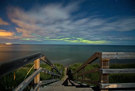 Stairs Leading Down To The Ocean With An Aurora Light In The Sky Above