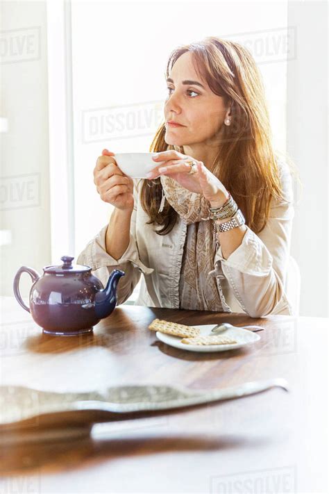 Caucasian Woman Drinking Tea At Table Stock Photo Dissolve