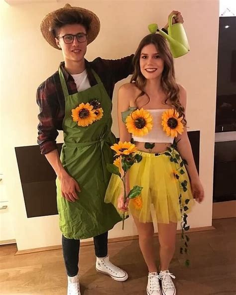 A Man And Woman Dressed In Costumes Standing Next To Each Other With Sunflowers On Their Aprons