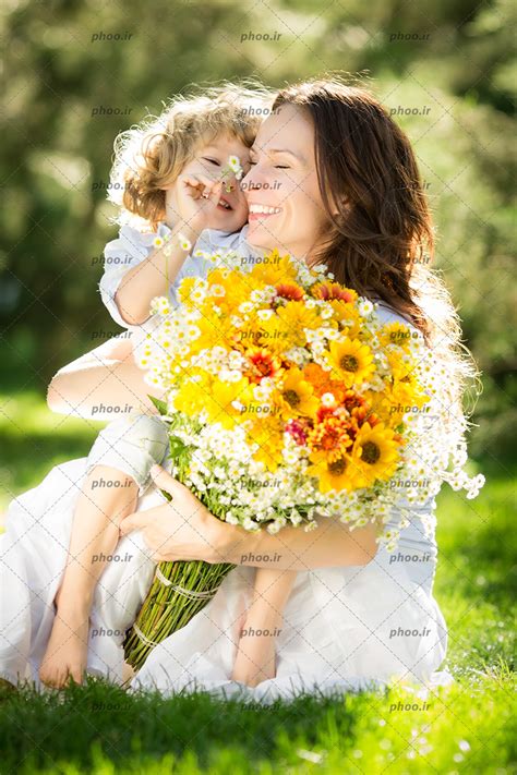عکس با کیفیت پسر بچه در آغوش مادر و مادر با یک دسته گل زیبا در دست عکس با کیفیت و تصاویر استوک