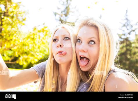 Two Sisters Having Fun Outdoors In A City Park In Autumn Taking Selfies
