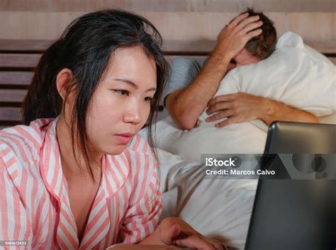 Angry And Frustrated Husband Moody In Bed Ignored By His Workaholic Asian Wife Or Internet