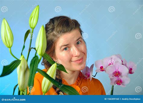 A Beautiful Girl With An Orchid In Her Hands Enjoys The Smell Of