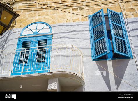 A Low Angle Of A Balcony With Blue Window Shutters On Brick Wall Stock