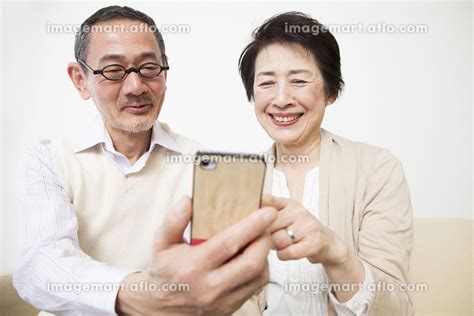 スマートフォンを見るシニアカップルの写真素材 23988740 イメージマート