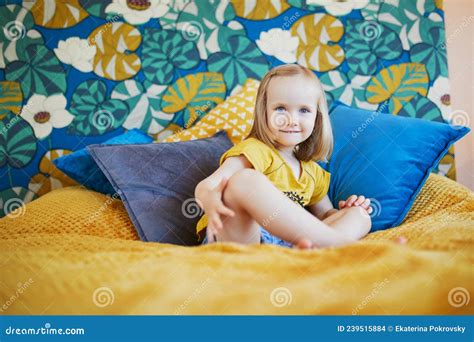 Adorable Little Girl Sitting On Bed In Nicely Decorated Bedroom Stock