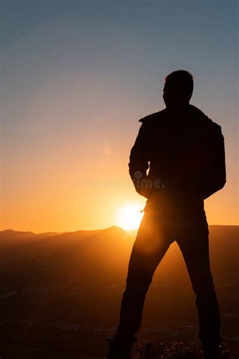 Silhouette Of Man Standing A Lone On Top Of Mountain With Orange