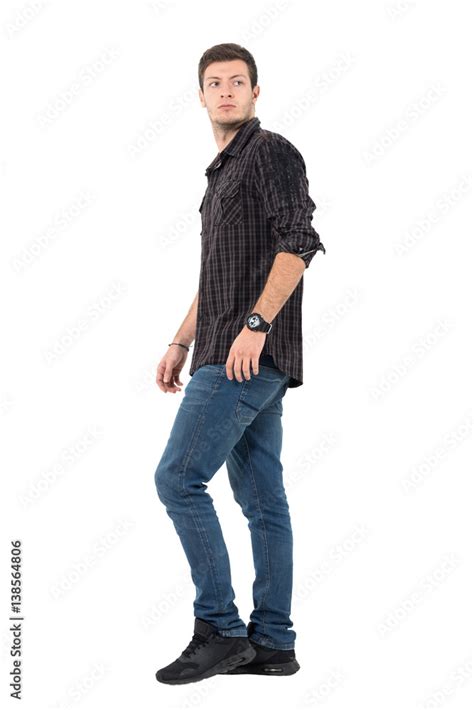 Side View Of Young Casual Man Walking Looking Back Over Shoulder Full