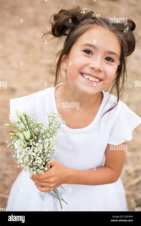 A Child Girl Holds A Bouquet Of White Flowers On A Blurry Background