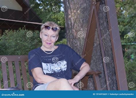 Mature Woman Sits On A Swinging Bench Smiles Stock Image Image Of