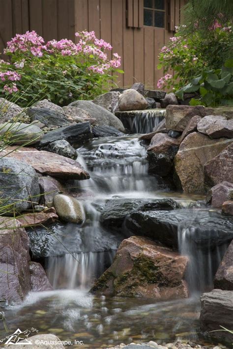 The previous owners of our house had some sort of water feature in the backyard. Pondless Waterfall at a Residential Home - Aquascape Inc. #backyardideas #waterfall #koi ...