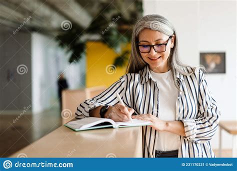 Una Mujer Madura De Pelo Blanco Alegre Sonriendo Mientras Escribe Notas Imagen De Archivo