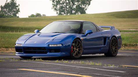 A Blue Sports Car Is Parked On The Side Of The Road In Front Of Some Grass