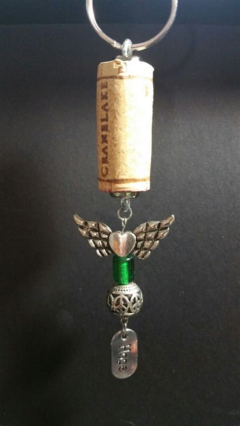 A Wine Bottle With An Angel Charm Hanging From Its Side On A Keychain