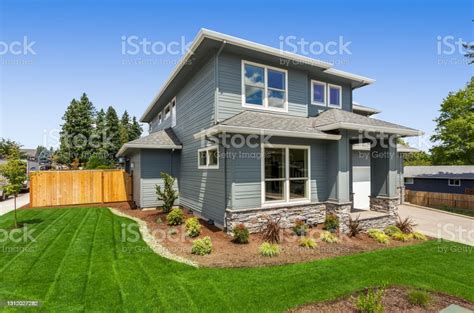 Beautiful Suburban Home Exterior On Bright Sunny Day With Green Grass