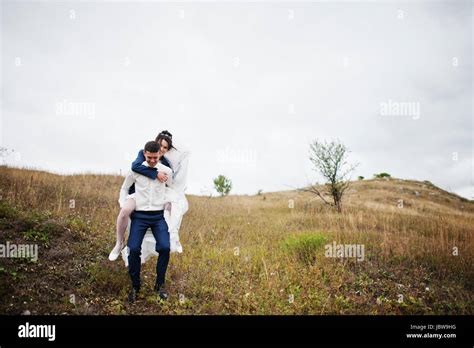 Happy Bride Riding Her Husbands Back On Their Wedding Day On The Of