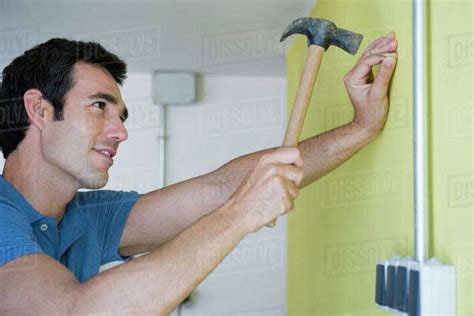 Man Hammering Nail Into Wall Stock Photo Dissolve