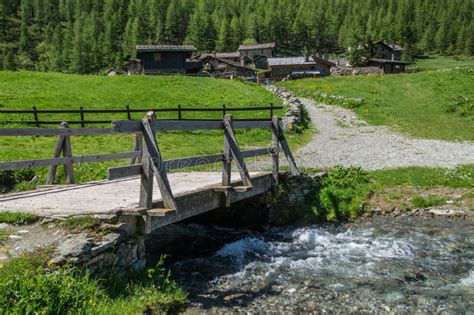 Beautiful View Of A Small Wooden Bridge Over The Rocky Flowing River