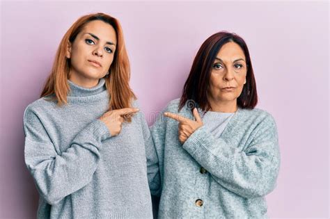 Latin Mother And Daughter Wearing Casual Clothes Pointing With Hand Finger To The Side Showing
