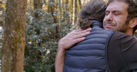 Sad Upset Crying Young Man Hugging Another Man Wearing A Down Vest