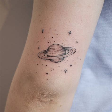 A Small Saturn Tattooed On The Back Of The Left Upper Arm By Marina