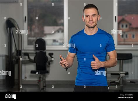 Gut Aussehend Personal Trainer Mit Stoppuhr Zeigt Daumen Hoch Zeichen In Ein Fitness Center