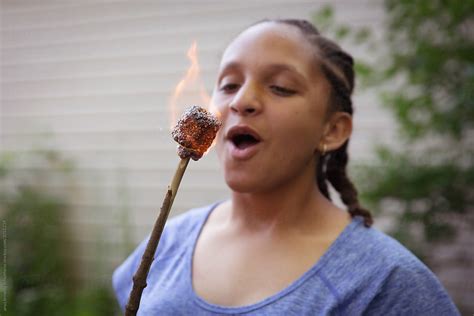 Teenager Blowing Out Her Burnt Marshmallow By Stocksy Contributor