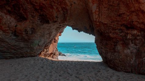 Download Wallpaper 1600x900 Beach Rock Cave Sea Sand Water
