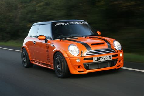 An Orange Mini Cooper Driving Down The Road