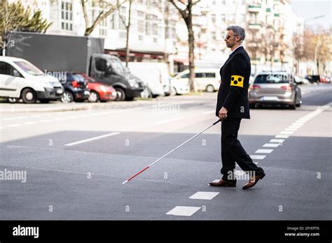 Blind Man Walking On Sidewalk Holding Stick Wearing Armband Stock Photo