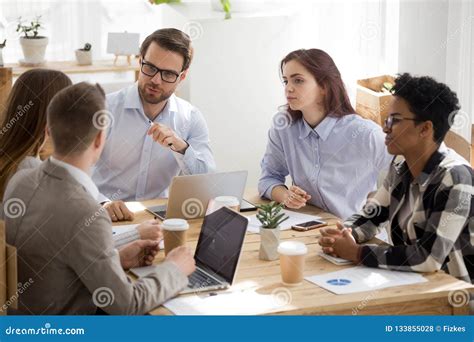 Diverse Millennial Employees Cooperating At Office Meeting Stock Photo