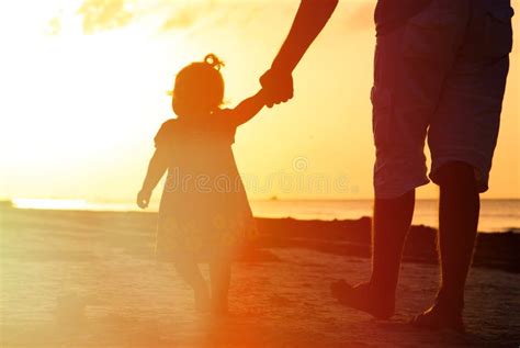 Padre Y Pequeña Hija Que Llevan A Cabo Las Manos En La Puesta Del Sol