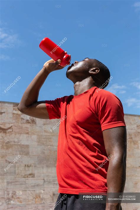 Low Angle Of Thirsty African American Athletic Male Drinking Fresh