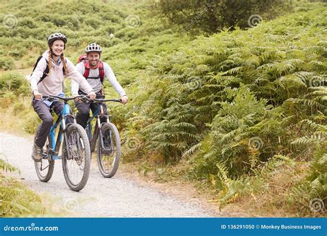 Young Adult Couple Riding Mountain Bikes In The Countryside Full