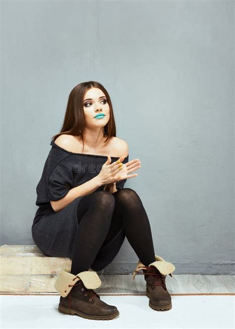 Portrait Of Fashion Full Body Model Seating Against Gray Wall Stock