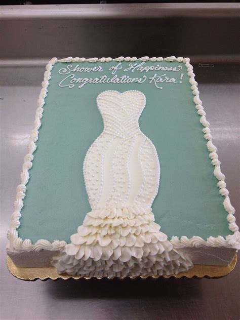 The Cake Is Decorated With White Frosting And Has A Dress On Its Side