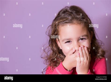 Portrait Of Laughing Little Girl Covering Mouth With Her Hands Stock