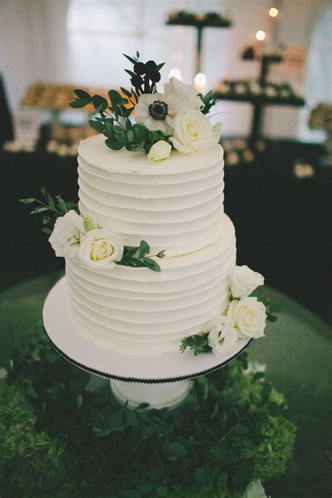 simple two tier wedding cake covered in real blossoms and greenery the cake is chocolate f