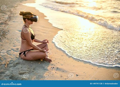 Woman In Vr Glasses Doing Yoga Padmasana On Ocean Beach In The Morning Girl Using Virtual