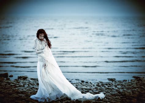 Beautiful Sad Girl In White Dress Standing On Sea Coast Stock Photo
