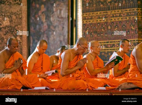 Thailand Bangkok Group Of Buddhist Monks Praying In Their Traditional Orange Dress Sitting In