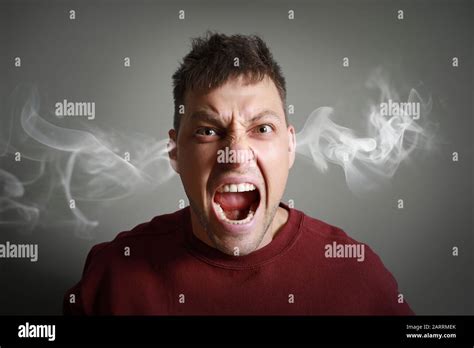 Portrait Of Angry Man With Steam Coming Out Of Ears On Grey Background