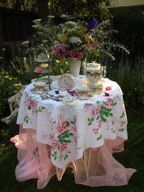 A Table That Has Some Tea On It In The Grass With Flowers And Plants