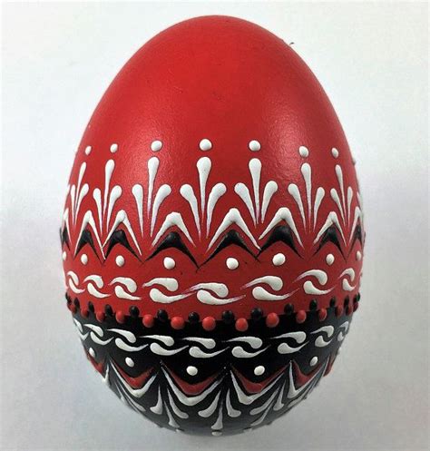 A Red And Black Painted Egg Sitting On Top Of A White Table