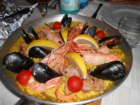 A Large Metal Pan Filled With Seafood And Mussels On Top Of Yellow Rice